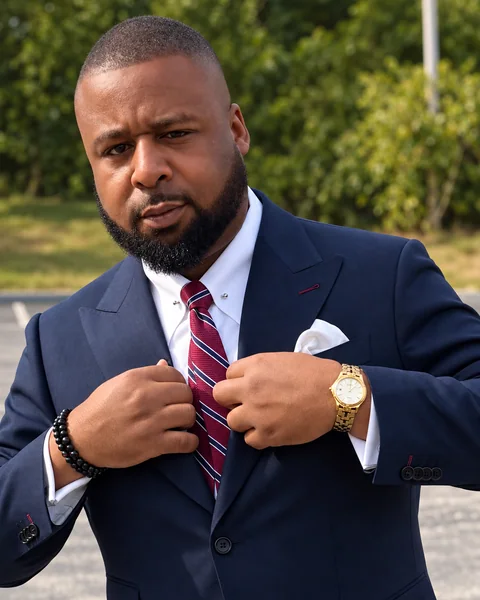 Justin Redditt in a navy Pearce Bespoke herringbone suit with a burgundy tie and white pocket square