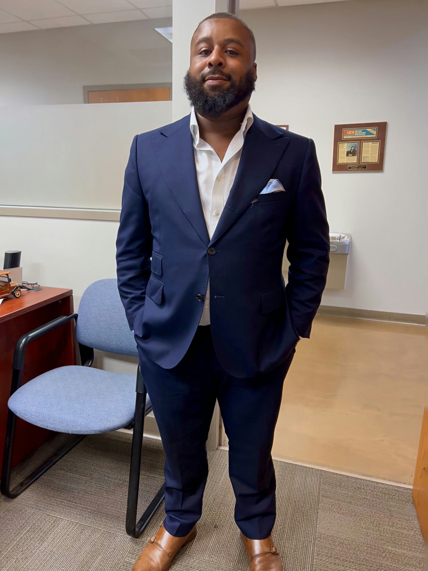 Justin wearing the navy tropical-wool suit with an open-collar white shirt and neatly arranged blue-and-white pocket square